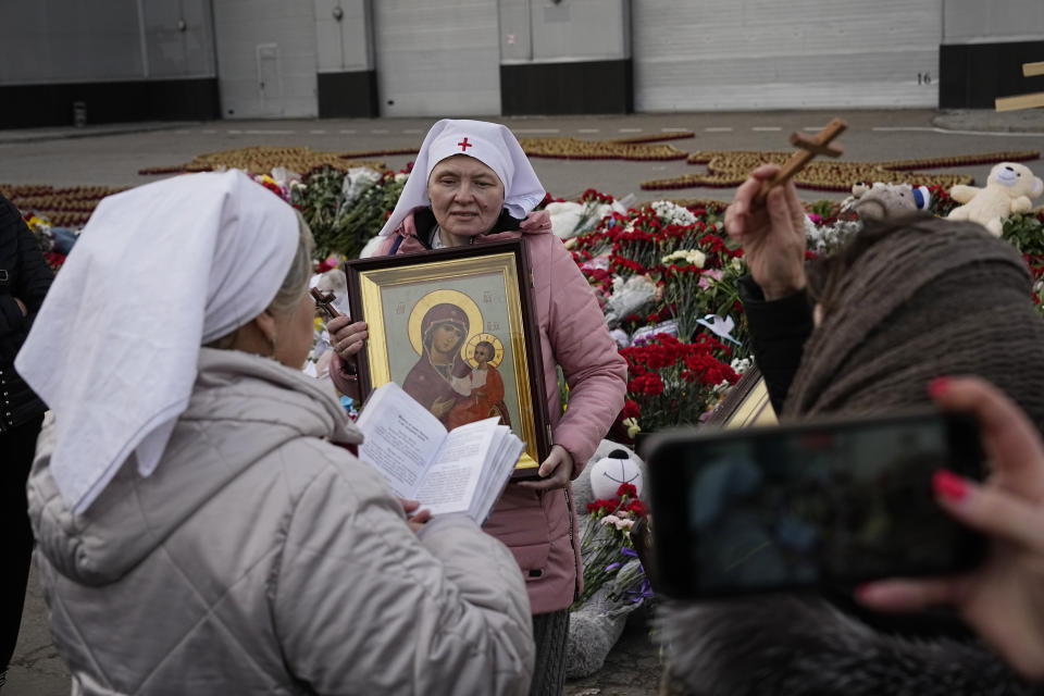 Orthodox believers attend a service at a makeshift memorial in front of the Crocus City Hall on the western outskirts of Moscow, Russia, Tuesday, March 26, 2024. Russian state news agency Tass says 22 victims of the concert hall attack that killed more than 130 people remain in serious condition in the hospital. (AP Photo/Alexander Zemlianichenko)