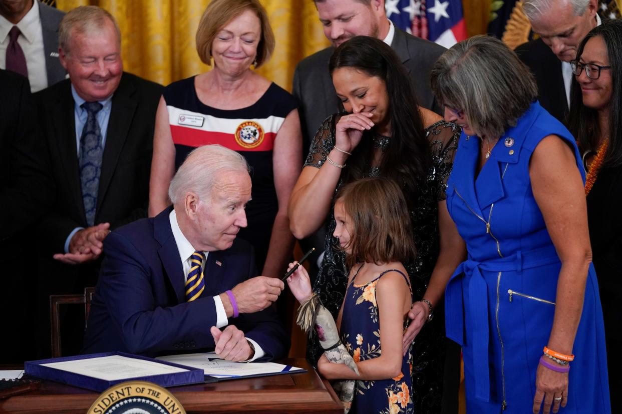 President Joe Biden gives the pen he used to sign the "PACT Act of 2022" to Brielle Robinson, daughter of Sgt. 1st Class Heath Robinson, who died of cancer two years prior, during a ceremony in the White House last year.