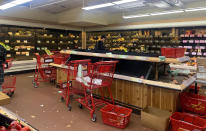 A man checks his cellphone near shelves at a New York City Trader Joe's market in disarray, Thursday, March 12, 2020. Coronavirus fears have some New Yorkers stocking up on essentials as uncertainty grows over what would be available and whether they would be able to leave home to get what they need. (Sarah Vaynerman via AP)