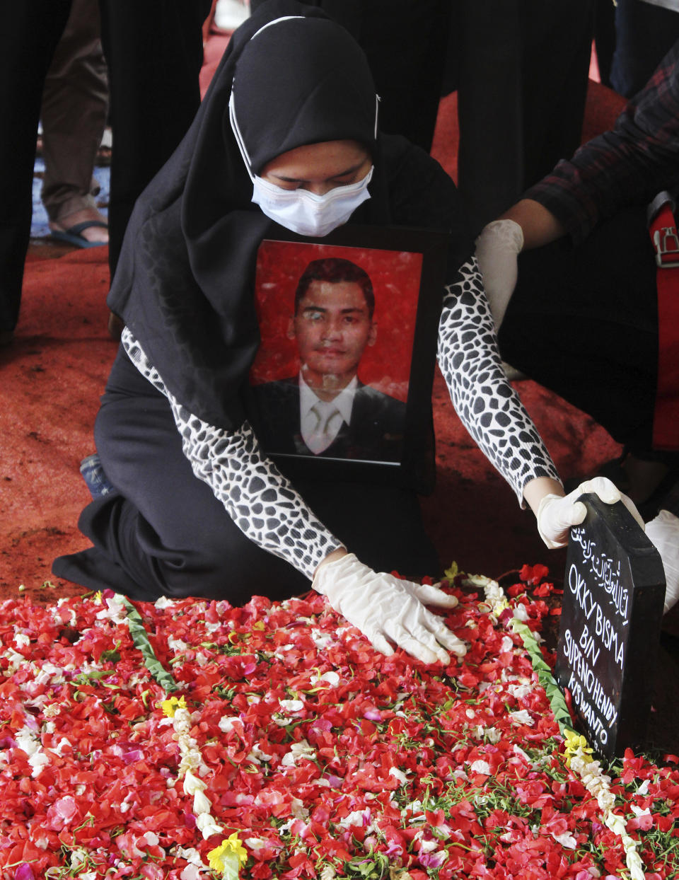 Aldha Refa, wife of steward Okky Bisma, one of victim Sriwijaya Air passenger jet crash, holds his photo during his funeral in Jakarta, Indonesia Thursday, Jan. 14, 2021. An aerial search for victims and wreckage of a crashed Indonesian plane expanded Thursday as divers continued combing the debris-littered seabed looking for the cockpit voice recorder from the lost Sriwijaya Air jet.(AP Photo)