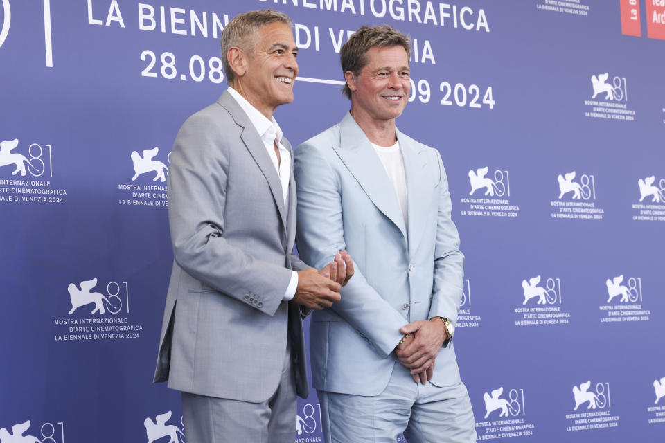 George Clooney and Brad Pitt pose in suits on the red carpet at the Venice International Film Festival, 2024