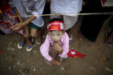 A child holds a National League for Democracy (NLD) party flag as he waits for Myanmar pro-democracy leader Aung San Suu Kyi during her campaign in her constituency of Kawhmu township outside Yangon September 21, 2015. REUTERS/Soe Zeya Tun