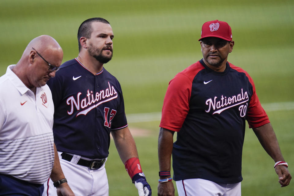 Washington Nationals' Kyle Schwarber, center, hobbles off the field next to trainer Paul Lessard, left, and manager Dave Martinez during the second inning of a baseball game against the Los Angeles Dodgers, Friday, July 2, 2021, in Washington. (AP Photo/Julio Cortez)