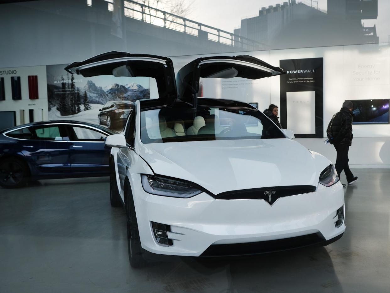 People walk near a Tesla vehicle