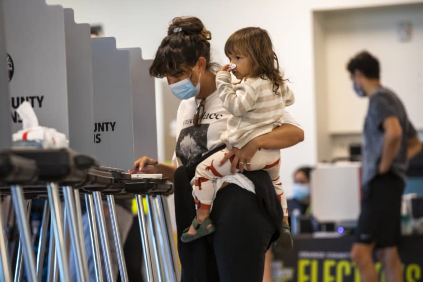 NEWPORT BEACH, CA - NOVEMBER 03: Billie Montague, 2, puts a vote sticker on her nose while watching her mom, Ashley Montague, vote at Marina Park Community Center on election day Tuesday, Nov. 3, 2020 in Newport Beach. (Allen J. Schaben / Los Angeles Times)