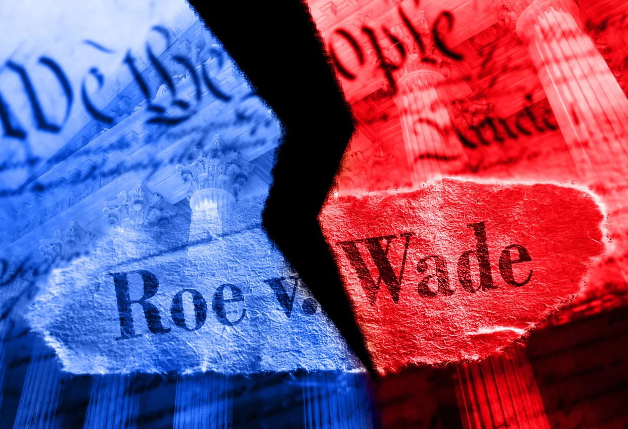 A photo illustration shows a piece of paper printed with the preamble to the Constitution and the words Roe v. Wade. The paper is torn down the middle, and the left half is blue, while the right half is red.