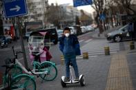 Child wearing a face mask rides a smart self-balancing scooter on a street, as the country is hit by an outbreak of the novel coronavirus, in Beijing