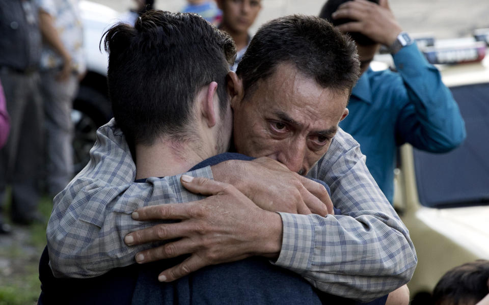 In this Oct. 9, 2019 photo, a father hugs his son outside the Migrant Assistance Office in San Salvador, El Salvador. Buses with deported Salvadorans, such as the son, arrive every day from the U.S. and Mexico. (AP Photo/Eduardo Verdugo)