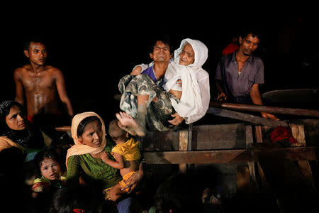 A man lifts an elderly woman from the boat as hundreds of Rohingya refugees arrive under the cover of darkness from Myanmar to the shore of Shah Porir Dwip, in Teknaf, near Cox's Bazar in Bangladesh, September 27, 2017. REUTERS/Damir Sagolj