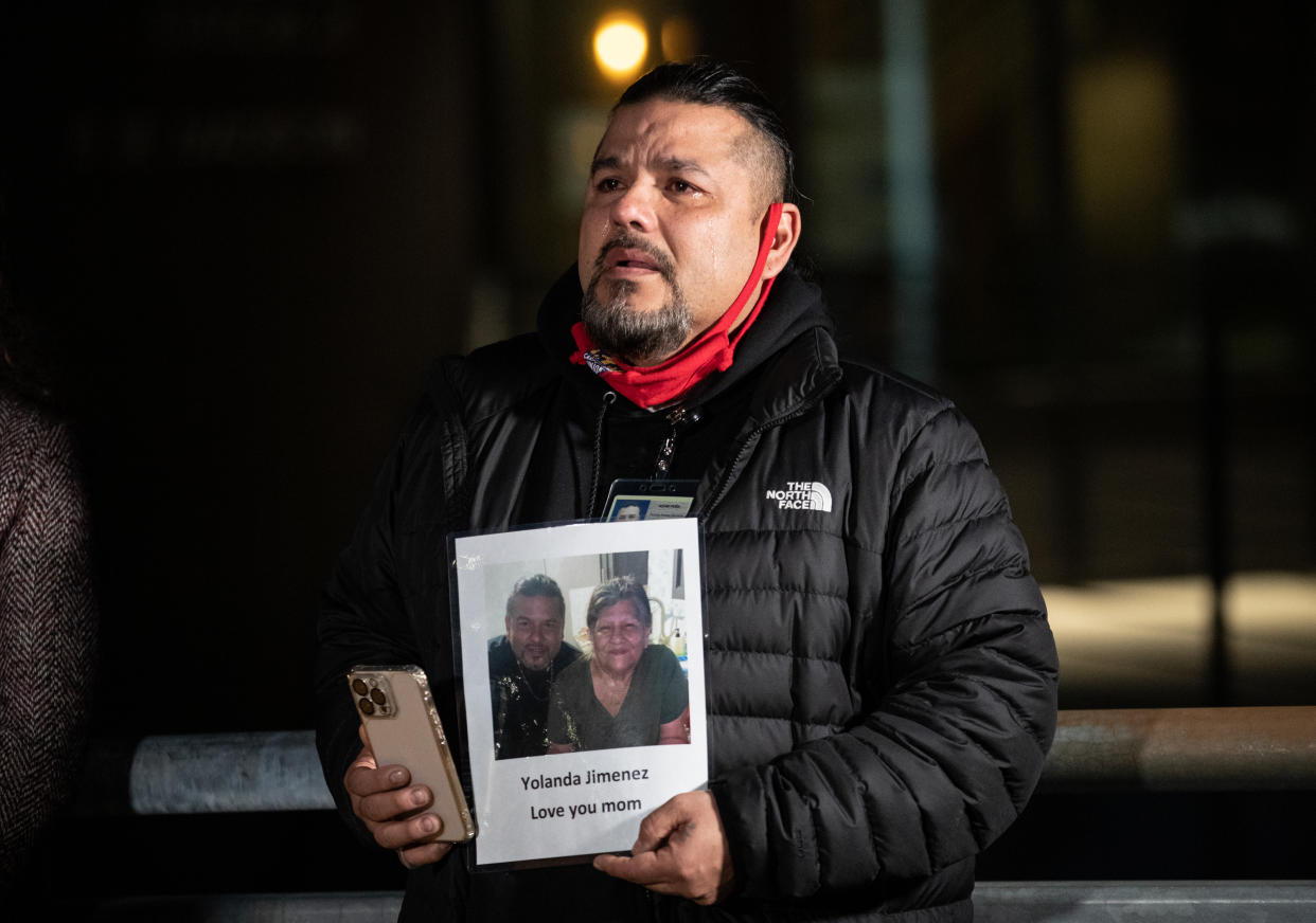 In a photo provided by Multnomah County, Adam Pena, a Multnomah County Aging and Disability Services employee who lost his mother, Yolanda Jimenez, to COVID-19 in 2021, holds a photo of his mother Thursday, March 10, 2022, in Portland, Ore., during an event held on the second anniversary of the first COVID-19 case in Portland. (Motoya Nakamura/Multnomah County via AP)