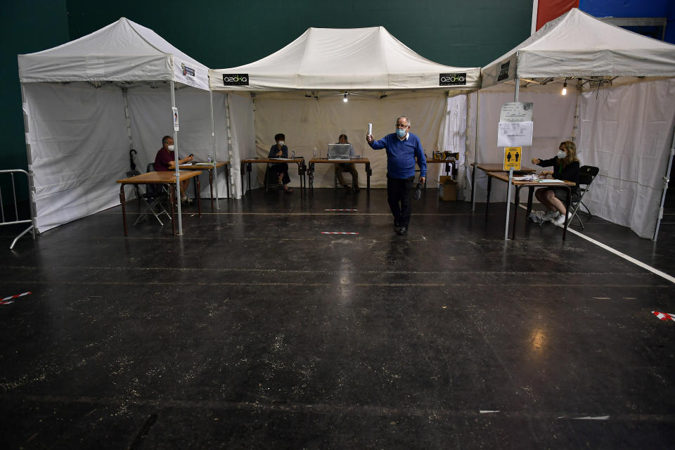 A man gestures after voting in a polling station, while wearing face mask to help curb the spread of the coronavirus, during the Basque regional election in the village of Ordizia, northern Spain, Sunday, July 12, 2020. Basque authorities are displaying special rules and practices in the protection against the coronavirus. (AP Photo/Alvaro Barrientos)
