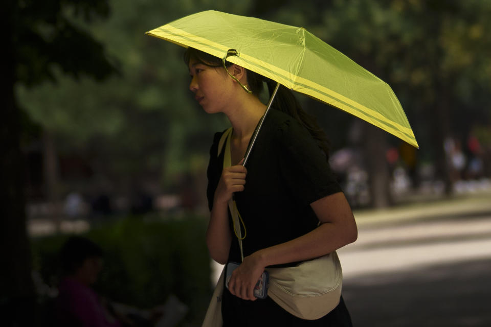 A woman shields herself from the sun at the Retiro park in Madrid, Spain, Monday, July 17, 2023. Spain’s Aemet weather agency said the heat wave this week “will affect a large part of the countries bordering the Mediterranean“ with temperatures in some southern areas of Spain exceeding 42 C (107 F). (AP Photo/Manu Fernandez)