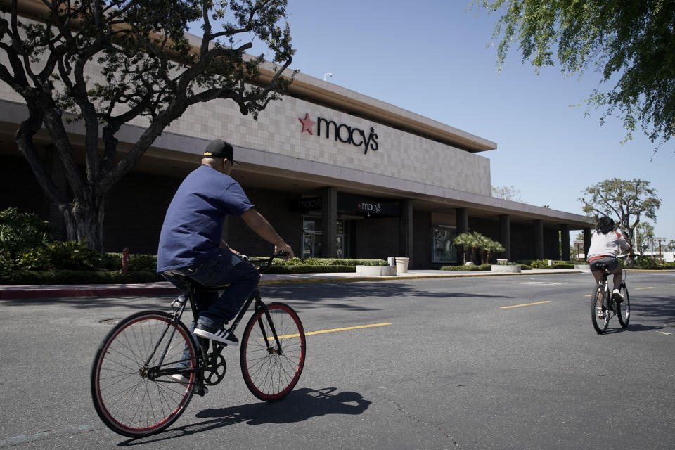 Bicyclists pass in front of a closed Macy's department store in Santa Ana, Calif., Monday, March 30, 2020. Macy's announced Monday is furloughing most of its 125,000 employees because coronavirus-fueled store closures have caused its sales to all but disappear. (AP Photo/Chris Carlson)