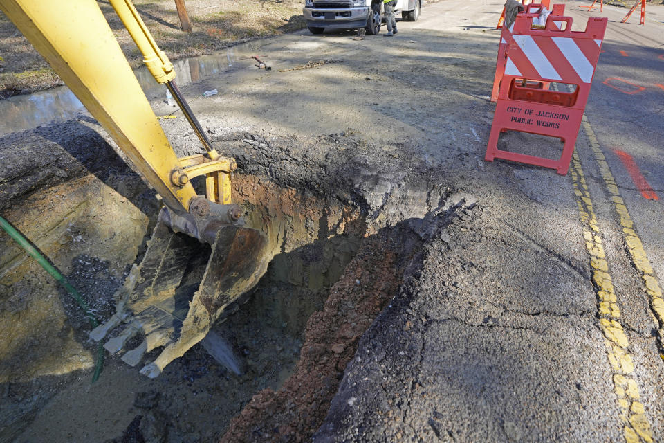 A backhoe unearths a waterline break under a street surface as a repair crew begins their work in south Jackson, Miss., Friday, Jan. 19, 2024, one of several breaks brought on by a period of freezing weather. Law enforcement agencies are investigating whether social media rumors about a potential water outage prompted people to quickly fill bathtubs with tap water in Mississippi's capital during a cold snap and cause a drop in pressure that temporarily made faucets run dry for thousands of customers on the city's long-troubled system. (AP Photo/Rogelio V. Solis)