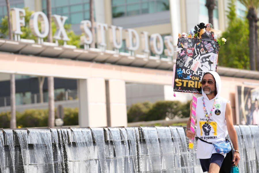 SAG-AFTRA member Newt Kane walks on a picket line outside Fox studios on Monday, Aug. 14, 2023, in Los Angeles. The Hollywood writers strike passed the 100-day mark as the film and television industries remain paralyzed by dual actors and screenwriters strikes. (AP Photo/Chris Pizzello)