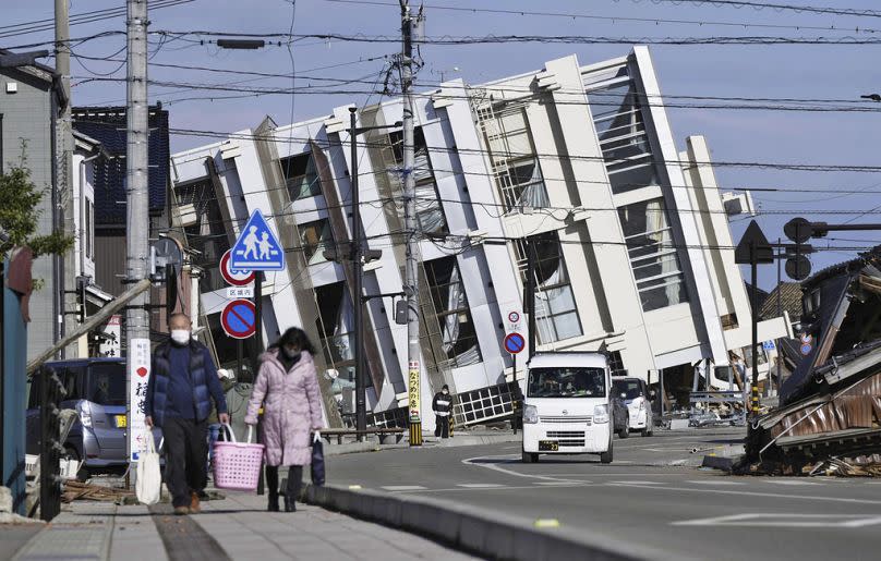 People make their way near a collapsed building due to an earthquake in Wajima, Ishikawa prefecture, Japan