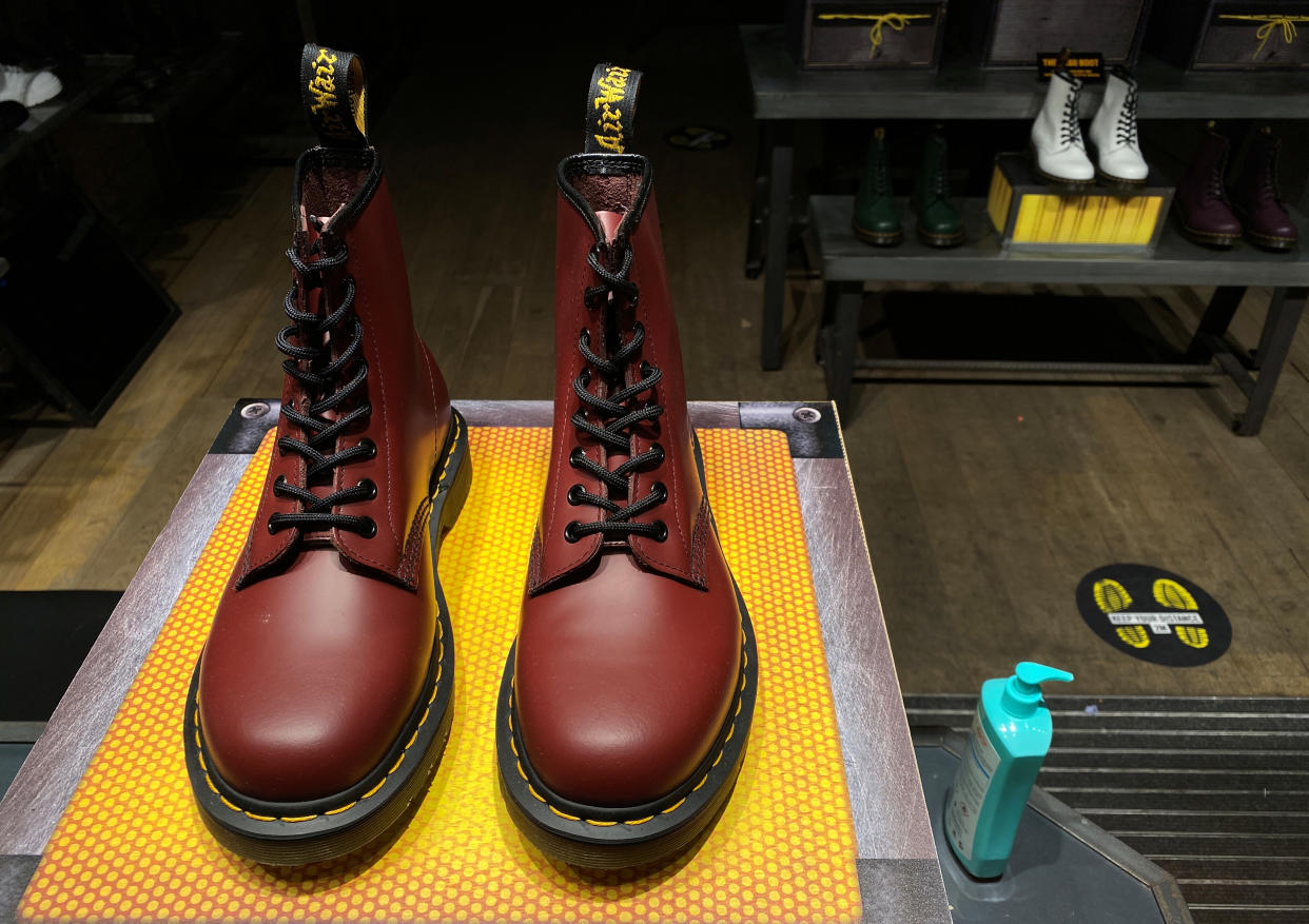 A pair of Dr. Martens boots, a bottle of hand sanitiser, and social distancing signage seen through the window of a Dr Martens shop amid the outbreak of the coronavirus disease (COVID-19) in London, Britain, September 17, 2020. REUTERS/Simon Newman