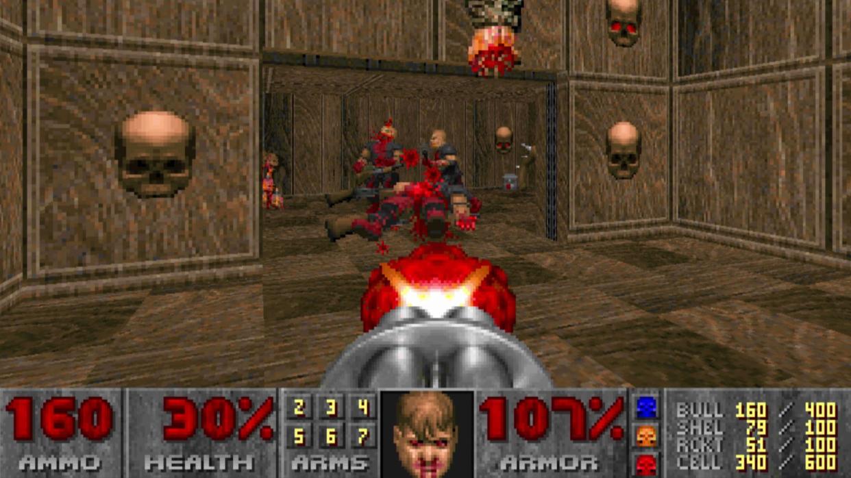  Screenshot from 1993 Doom showing enemies being shot in a room with skulls. 