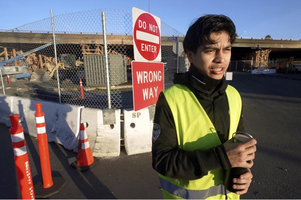 Private security guard David Delgado Hernandez, 19, guards the street access next to a burned section of Interstate 10 being rebuilt in Los Angeles, Saturday, Dec. 9, 2023. (AP Photo/Damian Dovarganes)