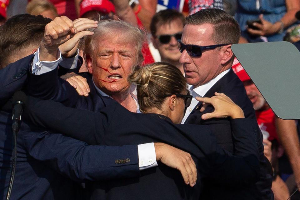 Donald Trump is seen with blood on his face surrounded by secret service agents as he is taken off the stage at a campaign event in Butler (AFP via Getty)