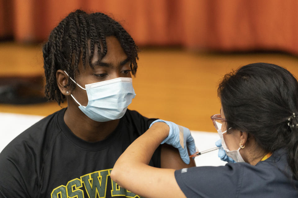 Zhaequan Brown, 19, gets the Pfizer COVID-19 vaccine at Lehman High School, Tuesday, July 27, 2021, in New York. The Centers for Disease Control and Prevention is urging everyone in K-12 schools to wear a mask when they return to class, regardless of vaccination status. (AP Photo/Mark Lennihan)