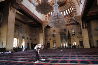 A man cleans a damaged mosque a day after an explosion hit the seaport of Beirut, Lebanon, Wednesday, Aug. 5, 2020. (AP Photo/Hussein Malla)