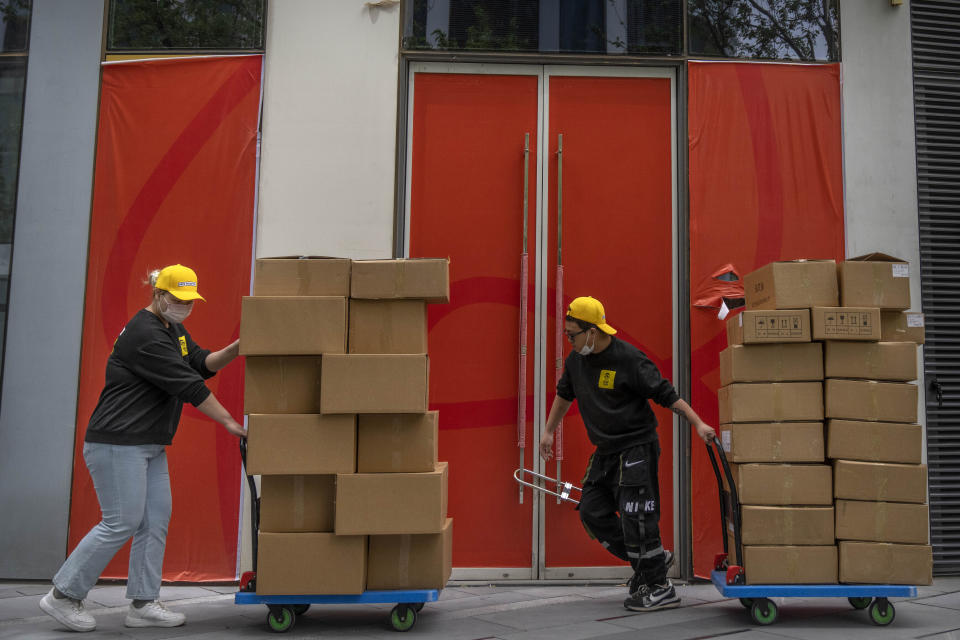 Workers pull carts loaded with boxes past an empty storefront at a shopping and office complex in Beijing, Friday, April 14, 2023. China’s economy grew 4.5% in the first quarter of the year, boosted by increased consumption and retail sales, after authorities abruptly abandoned the stringent "zero-COVID" strategy. (AP Photo/Mark Schiefelbein)