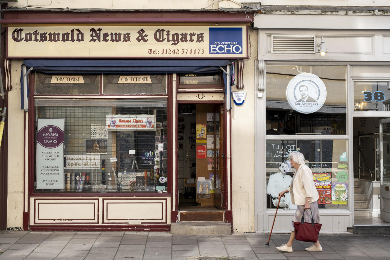 Elderly woman passes Cotswold News & Cigars newsagents on 15th September 2023 in Cheltenham, United Kingdom. Cheltenham also known as Cheltenham Spa, is sometimes known as 'the Garden Town of England', is a spa town on the edge of the Cotswolds in the county of Gloucestershire. Cheltenham is well known for it's Regency style architecture. (photo by Mike Kemp/In Pictures via Getty Images)