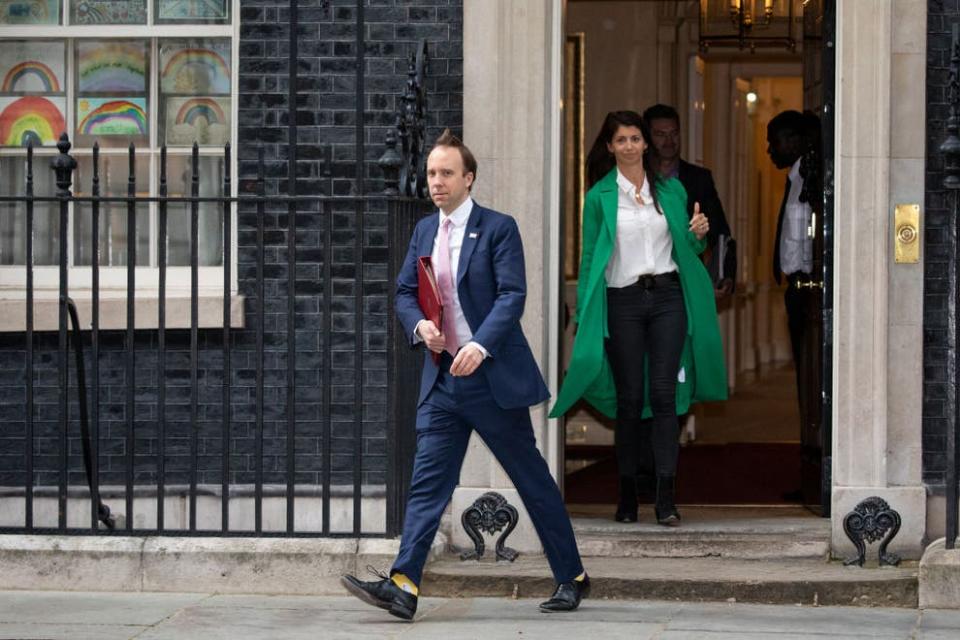 Matt Hancock leaves 10 Downing Street after the daily press briefing in May, with Gina Colandangelo in the green coat (Getty Images)