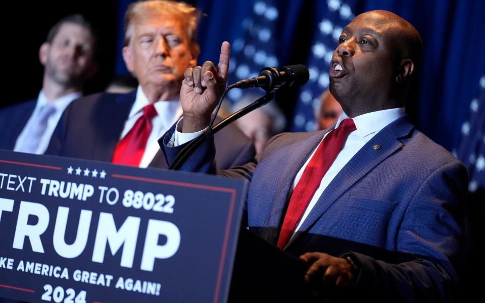 Donald Trump listens as Sen. Tim Scott speaks at a primary election night party in South Carolina