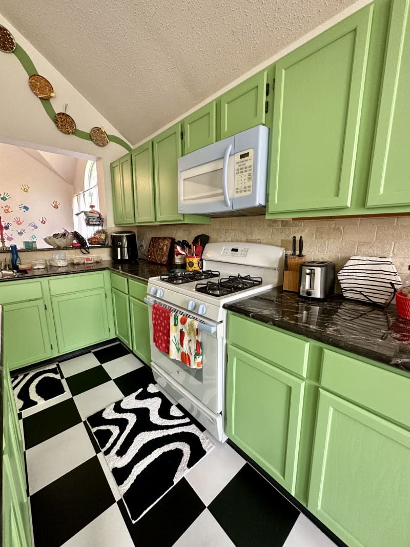 Green painted cabinets with blue handles in kitchen.