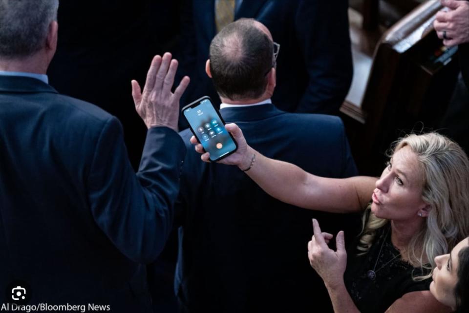 Marjorie Taylor Greene tries to hand a cell phone to a member of Congress during the Speaker vote.