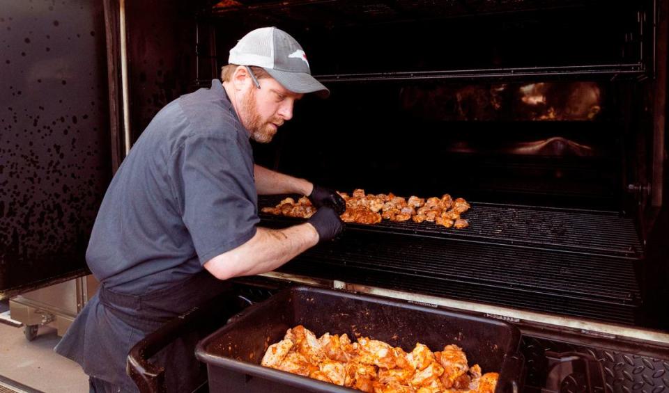 Pitmaster Matt Barry adds chicken wings to the Oyler smoker at Midwood Smokehouse in Raleigh, N.C., Wednesday, Feb. 8, 2023.