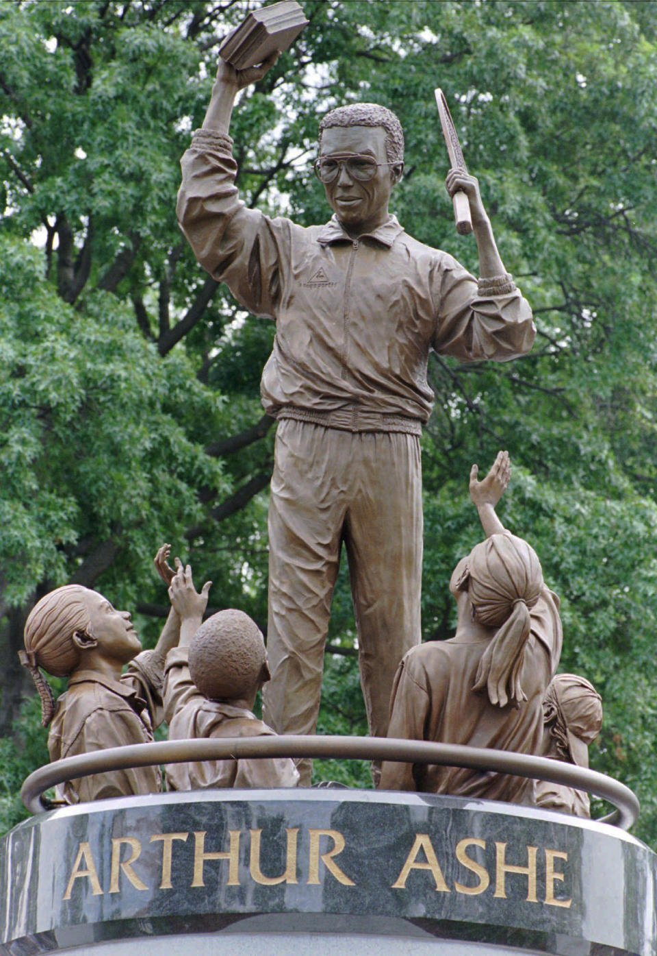 FILE - In this July 10, 1996 file photo, the statue of Arthur Ashe surrounded by children by sculptor Paul Di Pasquale is unveiled on Monument Ave. in Richmond, Va. The statue of the African American tennis legend has been vandalized with the words “White Lives Matter.” Richmond Police said they were alerted to the vandalism Wednesday, June 17, 2020. Police say red paint on the statue itself was already being cleaned off by community members. (AP Photo/Steve Helber, File)