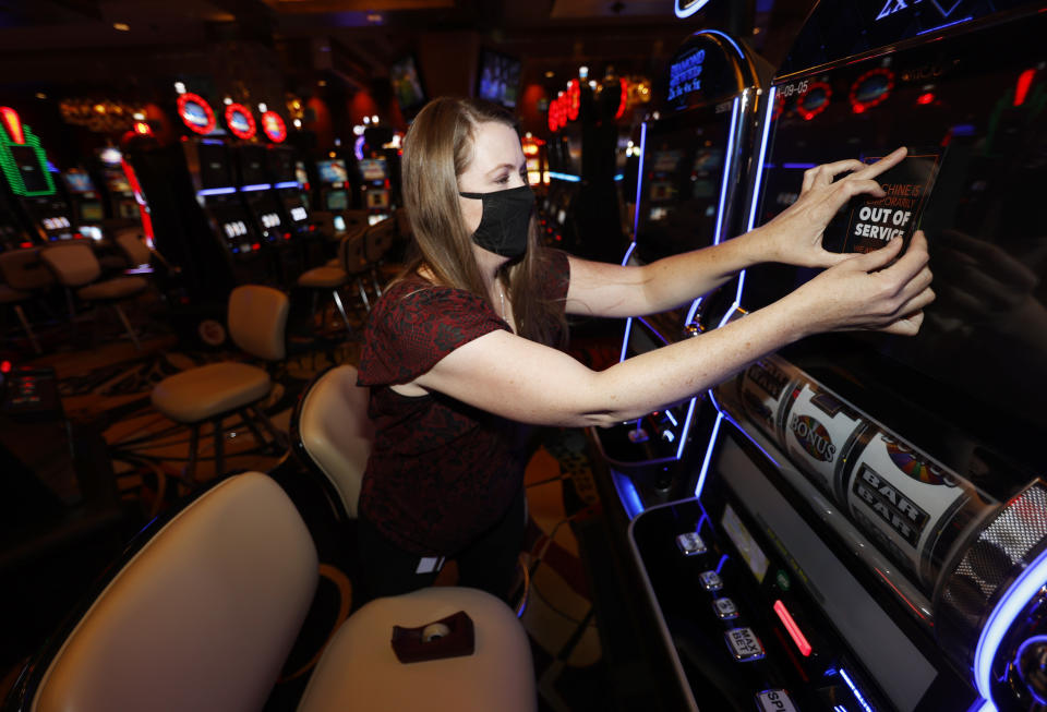 Alyssa Brunette affixes an out of service sign on a slot machine shut off to meet social-distancing requirments as workers prepare for the reopening of Monarch Casino and Resort after a three-month closure because of the spread of the new coronavirus Tuesday, June 16, 2020, in Black Hawk, Colo. Casinos in Black Hawk, nearby Central City and Cripple Creek have been granted approval from the state to open on a limited basis as coronavirus cases diminish in Colorado. (AP Photo/David Zalubowski)