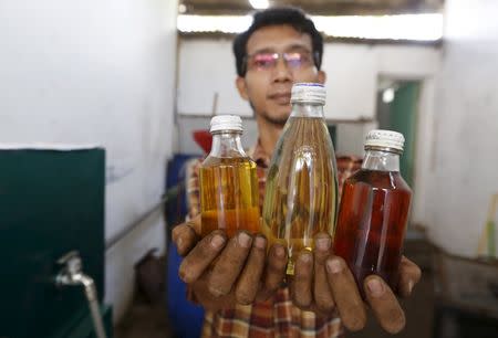 Hamidi holds three bottles containing three different fuels, derived from burning plastic waste, at his workshop at TPA Rawa Kucing in Tangerang, Banten province, Indonesia March 17, 2016. REUTERS/Beawiharta