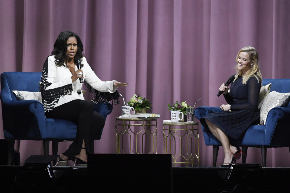 The former FLOTUS and actress Reese Witherspoon have a laugh together on stage during Becoming: An Intimate Conversation at the Pepsi Center in Denver, Colorado on Dec. 13.