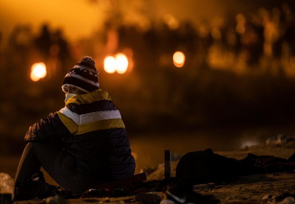 A migrant watches fellow migrants from the south bank of the Rio Grande in Juárez who had crossed to seek asylum in El Paso, Texas on Dec. 19, 2022.