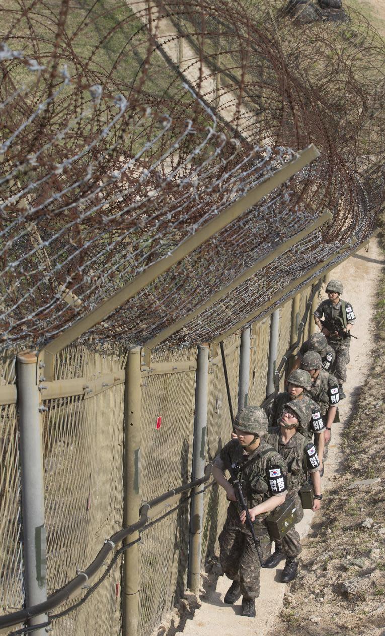 South Korean army soldiers patrol along the barbed-wire fence at the demilitarized zone (DMZ) in Cheorwon, South Korea, Tuesday, May 13, 2014. North Korea warned Tuesday that a South Korean official would pay a high price for saying the North "must disappear soon" in an escalation of rhetoric between the rivals. (AP Photo/Yonhap, Lim Byung-shik) KOREA OUT