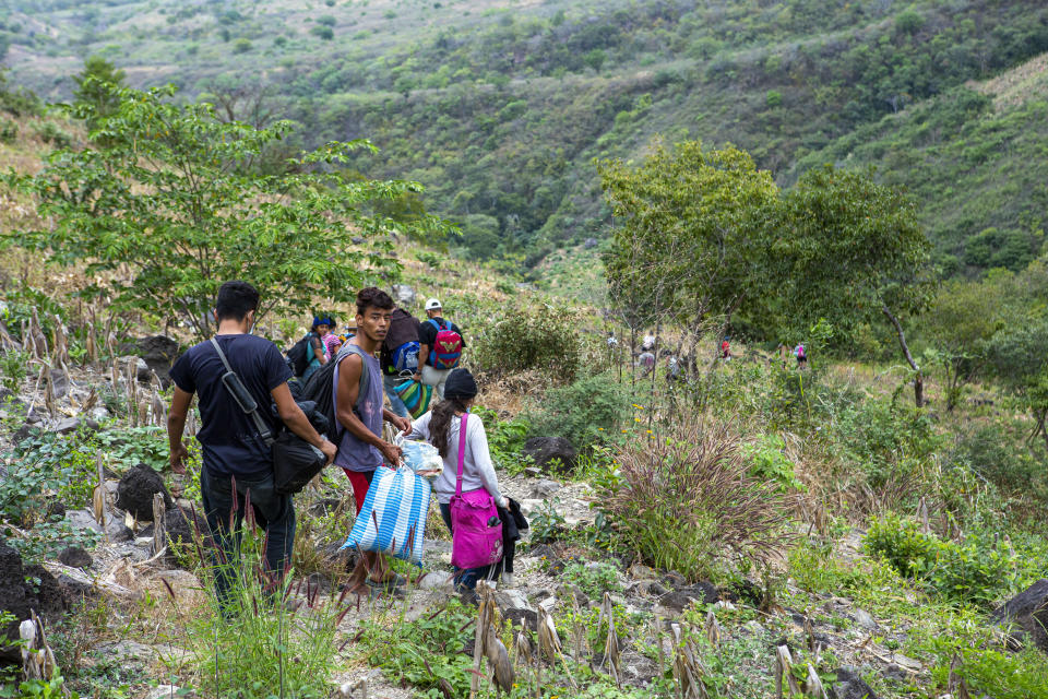 Honduran migrants trying to reach the U.S. take a path through the mountains to avoid the highway police checkpoints, in Chiquimula, Guatemala, Tuesday, Jan. 19, 2021. A once large caravan of Honduran migrants that pushed its way into Guatemala last week had dissipated by Tuesday in the face of Guatemalan security forces. (AP Photo/Oliver de Ros)