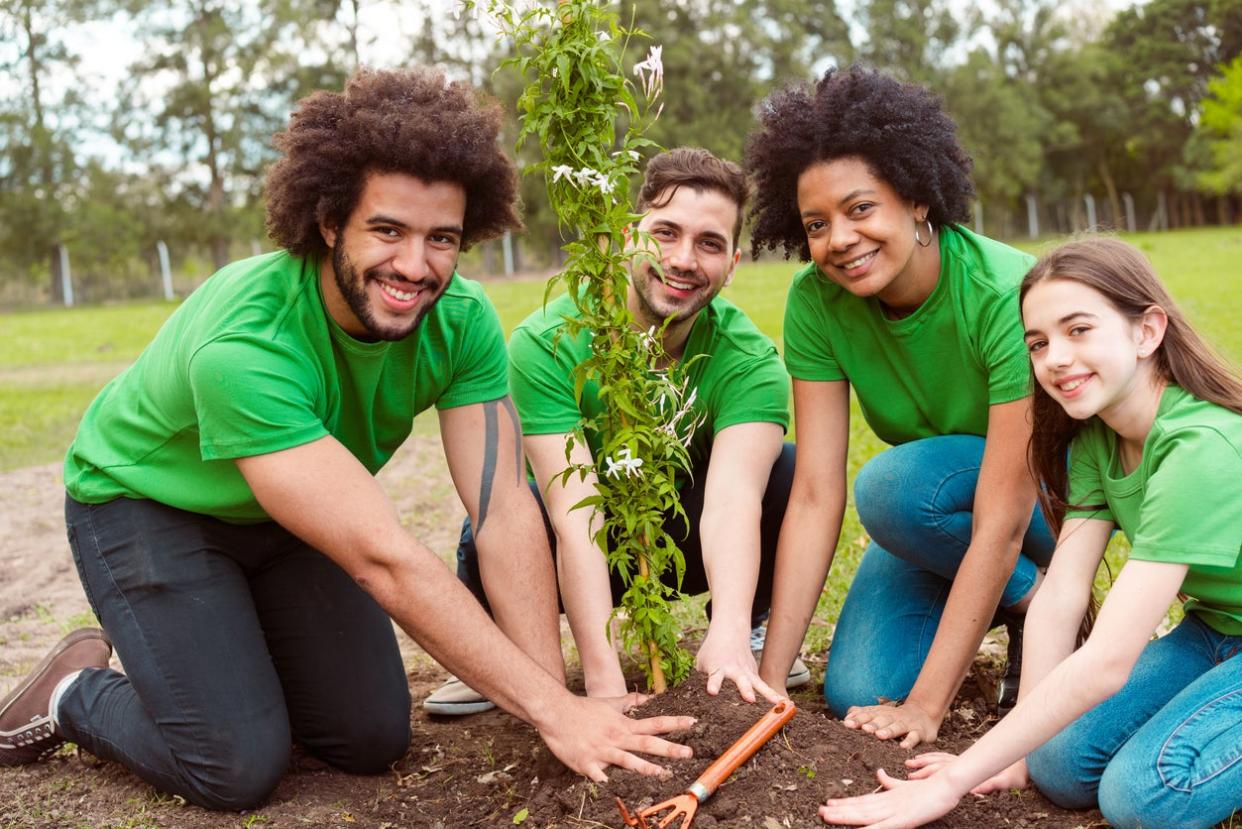 Happy volunteers planting plant in public park