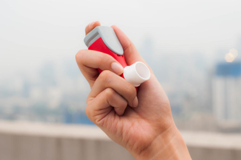 A young woman is using an asthma inhaler outdoor