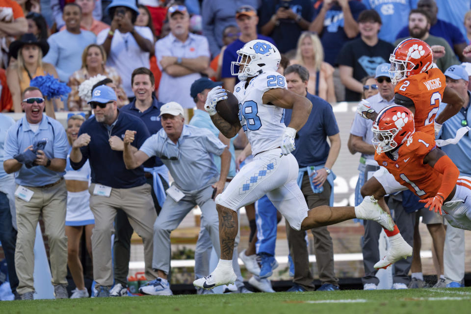 North Carolina running back Omarion Hampton (28) runs with the ball while pursued by Clemson safety Andrew Mukuba (1) and cornerback Nate Wiggins (2) during the first half of an NCAA college football game Saturday, Nov. 18, 2023, in Clemson, S.C. (AP Photo/Jacob Kupferman)