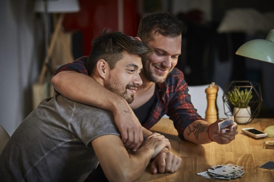 gay couple hugging at table with playing cards