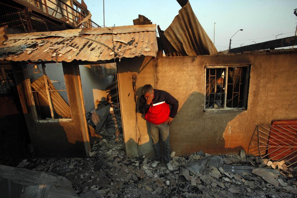 A man cries next to the remains of his house after a forest fire destroyed it in Valparaiso, Sunday, April 13, 2014. A raging fire leaped from hilltop to hilltop in this port city, killing at least 11 people and destroying more than 500 homes. More than 10,000 people were evacuated. (AP Photo/Luis Hidalgo)