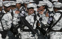 FILE - A National Guardsman smiles while stretching before the start of a presentation ceremony at a military field in Mexico City, June 30, 2019. The National Guard which includes federal police, marines, soldiers and new recruits was created to stem endemic violence and restore peace in the country. (AP Photo/Christian Palma, File)