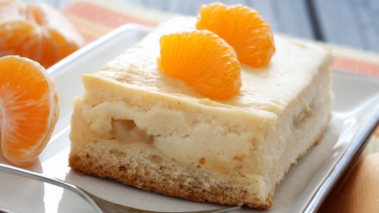 slice of vanilla layered cake with frosting and oranges