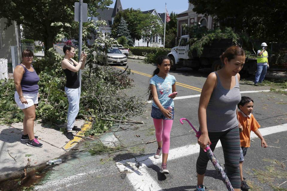 Pedestrians walk past storm cleanup crews on Beach Street in Revere, Massachusetts, July 28, 2014. Police and emergency crews in Revere, outside Boston, scrambled to clean up after a rare tornado touched down on Monday, downing power lines, damaging homes and overturning at least one car. The National Weather Service confirmed that a tornado touched down during a storm that brought heavy rains, lightning and flooding to Boston and many of its northern suburbs. State emergency management officials said they were not aware of major injuries or fatalities from the storm. (REUTERS/Dominick Reuter)