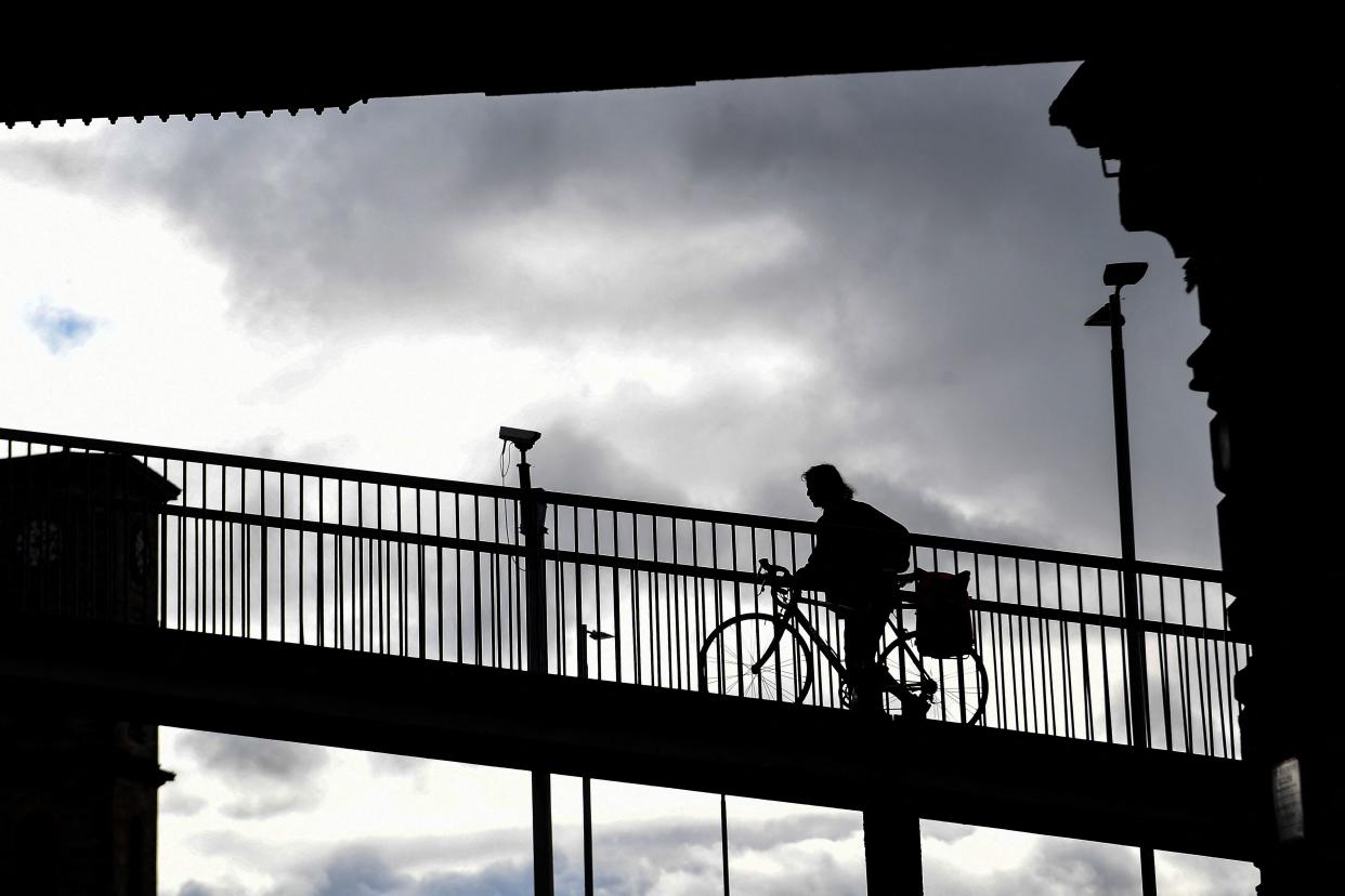 A cyclist pushes a bike over a footbridge near the COP26 climate summit venue in Glasgow on October 13, 2021. (Photo by Andy Buchanan / AFP) (Photo by ANDY BUCHANAN/AFP via Getty Images)