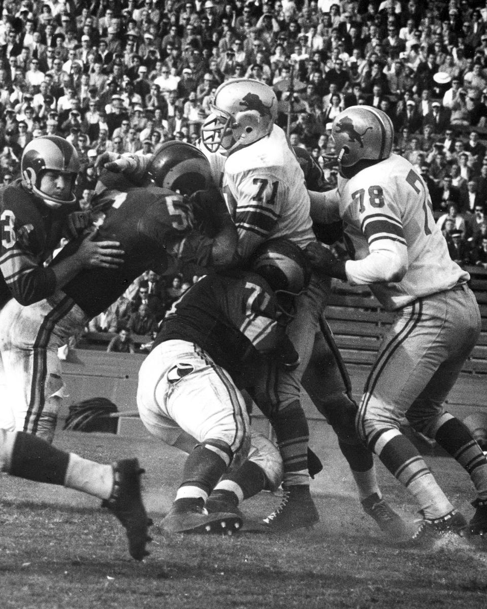 FILE- In this undated file photo, unidentified members of the Los Angeles Rams NFL football team try and stop Detroit Lions defensive tackle Alex Karras (71) during a game in Michigan. For all the acclaim that followed, Karras died at age 77 in 2012 without one of the honors he coveted most: a bust in the Pro Football Hall of Fame. Better late than never, Karras will be formally enshrined as part of the Hall’s Centennial Class of 2020. (Detroit Lions via AP)